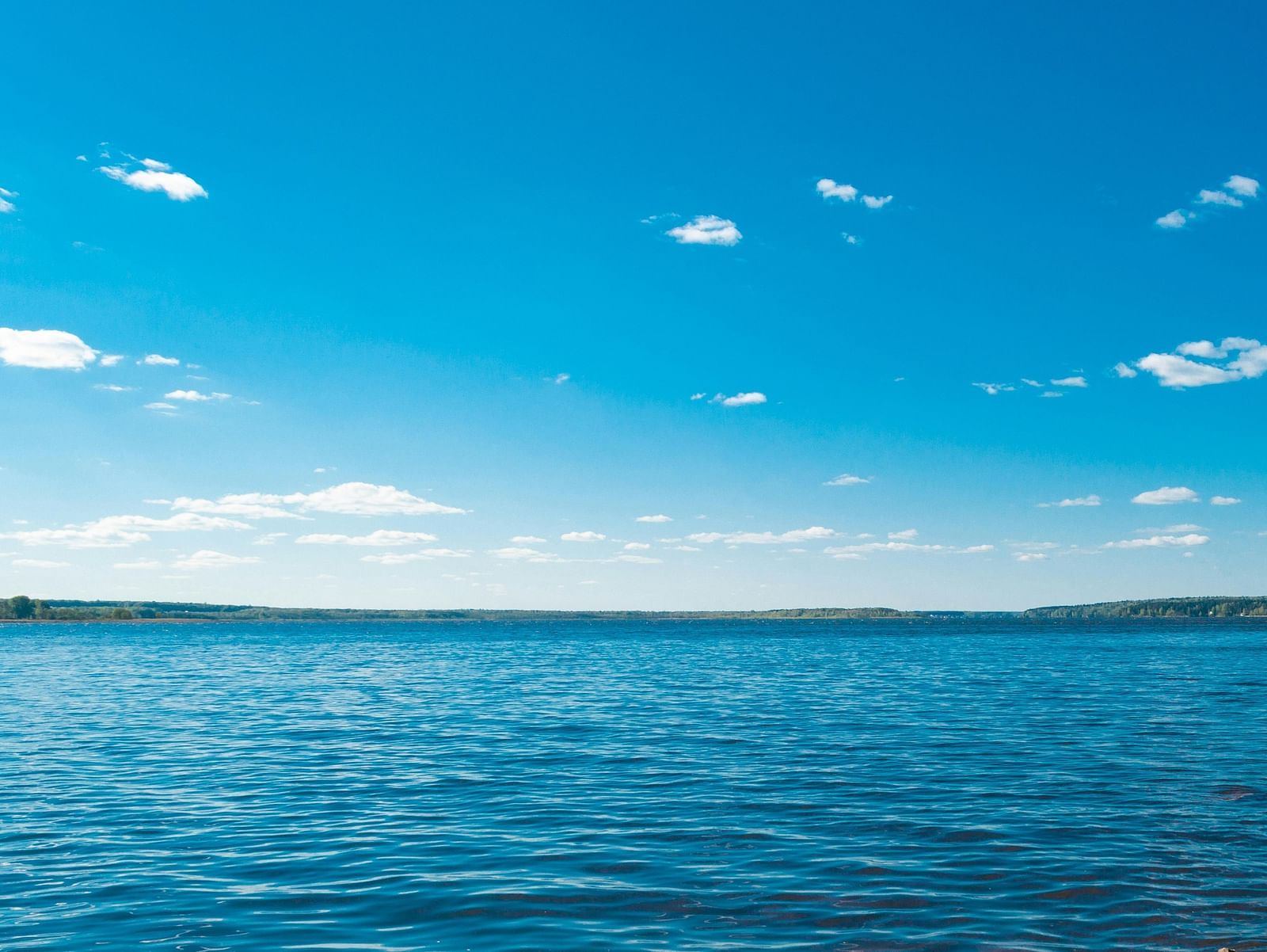 Blue lake with clear sky and mountains in the background.