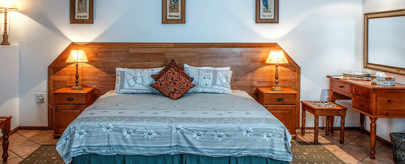 Front view shot of a bedroom featuring a double bed with bright table lamps besides the bed on both sides.