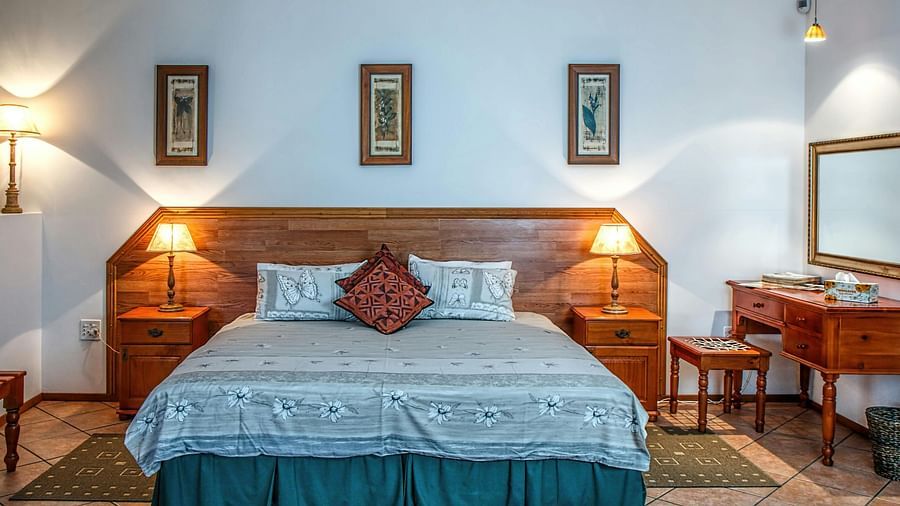 A bedroom with a wooden bed, patterned bedding, and two bedside tables with lamps