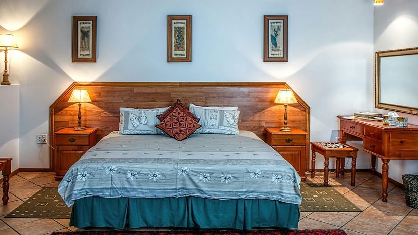 A bedroom with a wooden bed, patterned bedding, and two bedside tables with lamps