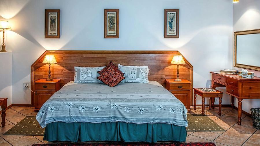 A bedroom with a wooden bed, patterned bedding, and two bedside tables with lamps