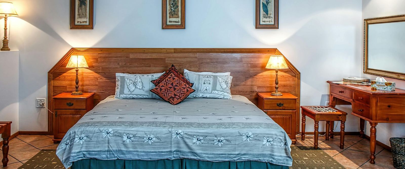 Front view shot of a bedroom featuring a double bed with bright table lamps besides the bed on both sides.