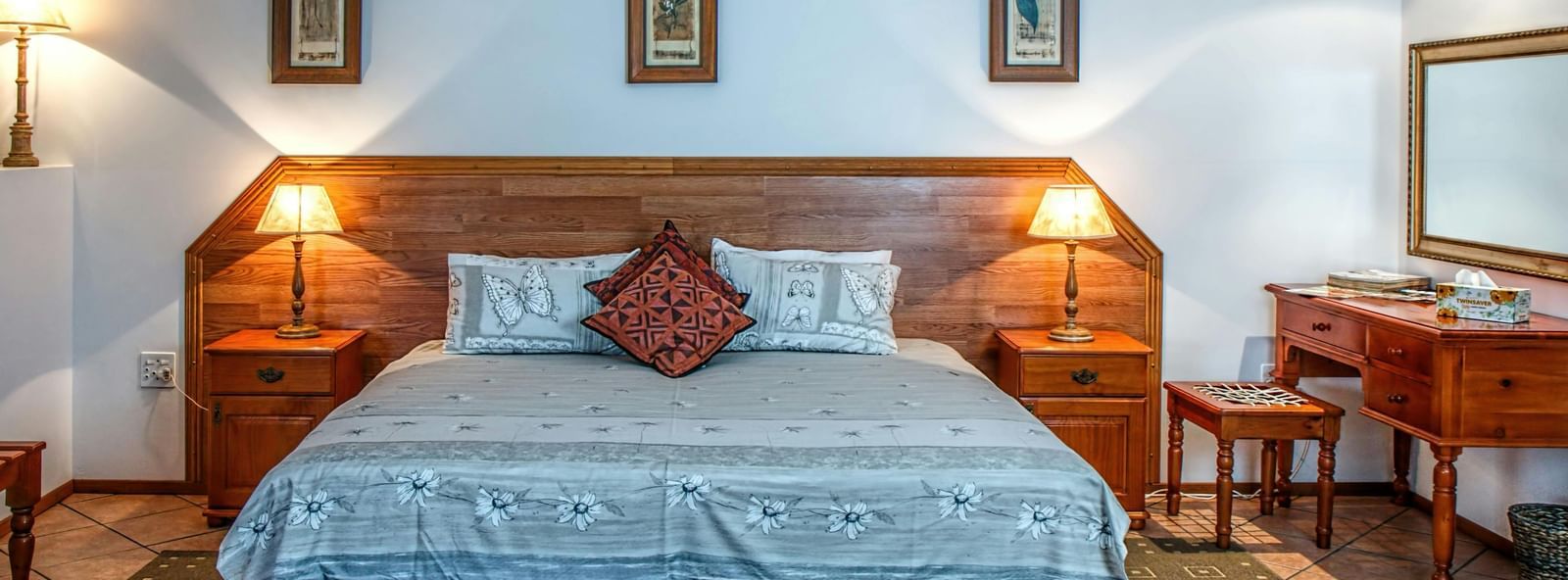 Cosy room with a large neatly made bed, wooden furniture, and framed wall art