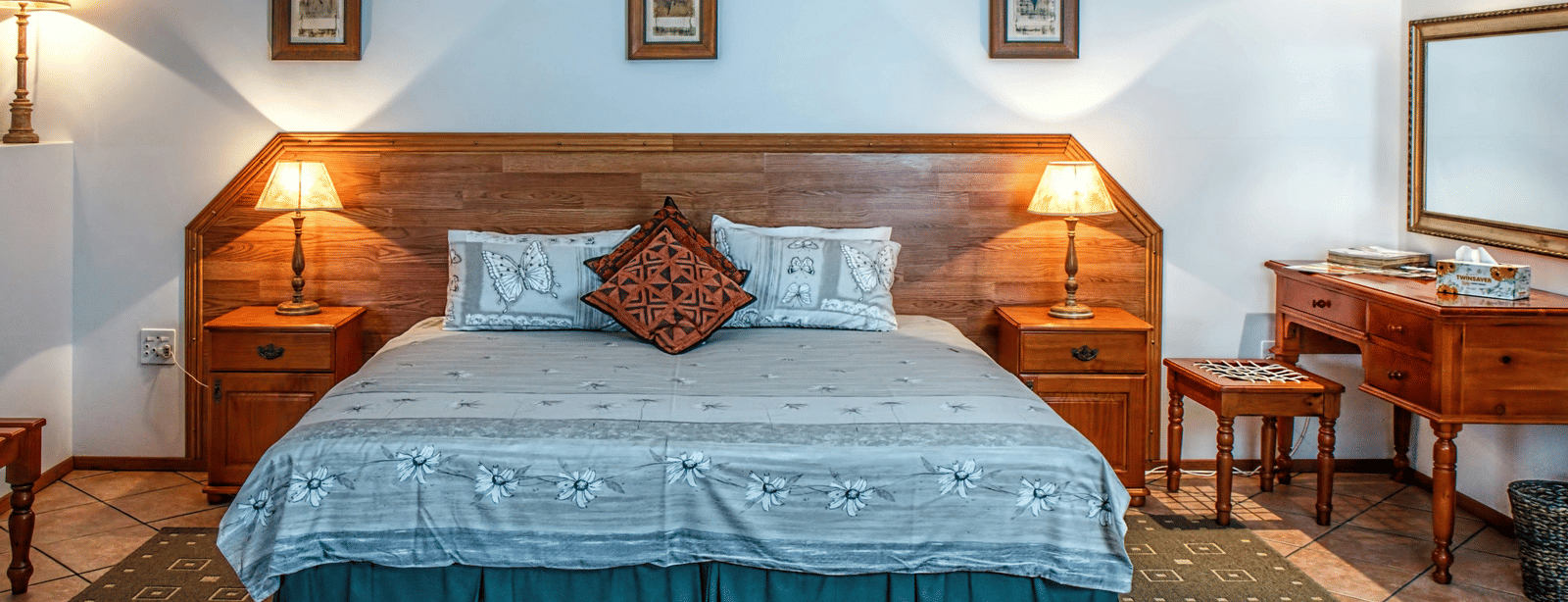 Front view shot of a bedroom featuring a double bed with bright table lamps besides the bed on both sides.