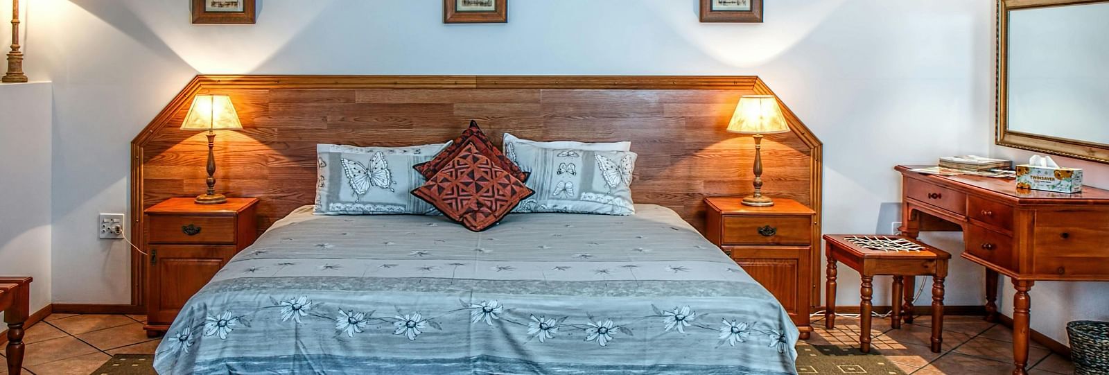 Front view shot of a bedroom featuring a double bed with bright table lamps besides the bed on both sides.
