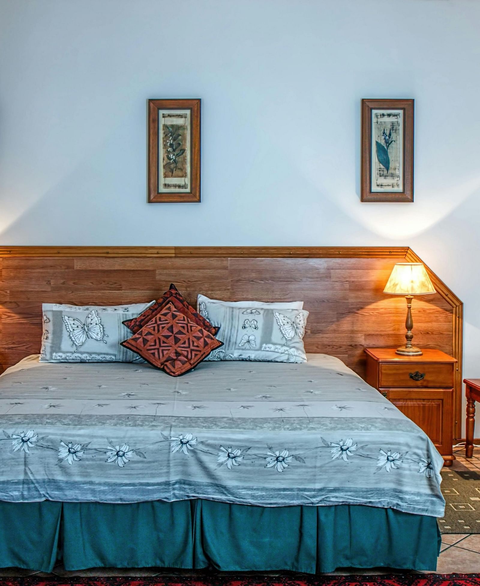 Front view shot of a bedroom featuring a double bed with bright table lamps besides the bed on both sides.