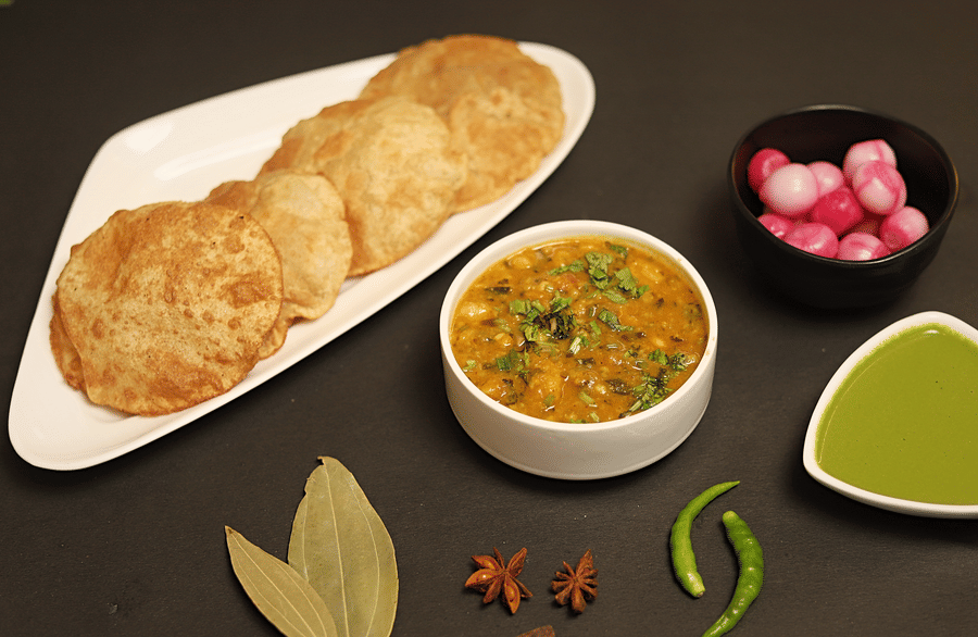 An plate of chole bhature served with green sauce and onions at a restaurant in Five Elements Hotels North Avenue, Delhi