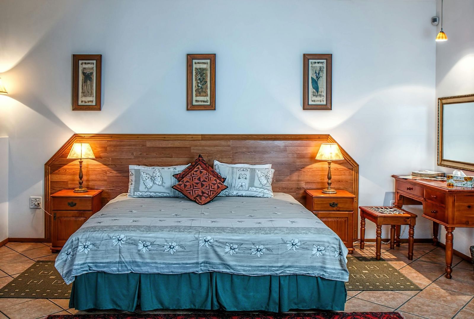 Front view shot of a bedroom featuring a double bed with bright table lamps besides the bed on both sides.