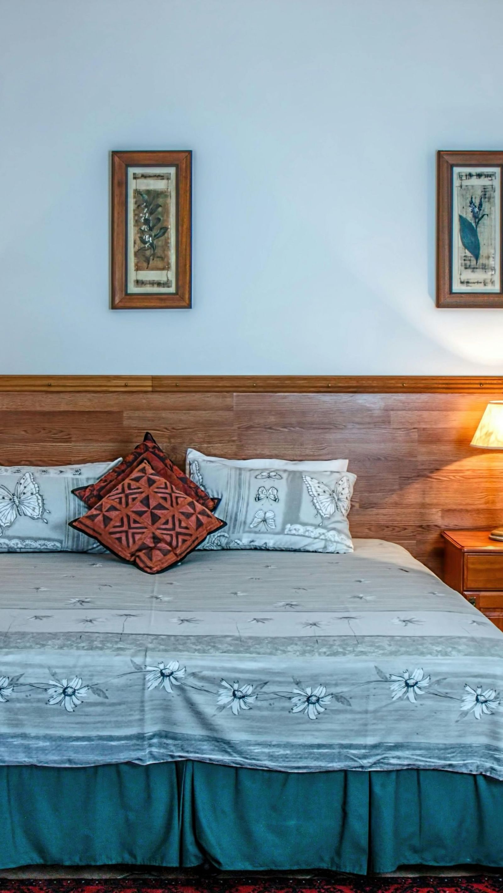 Cosy room with a large neatly made bed, wooden furniture, and framed wall art