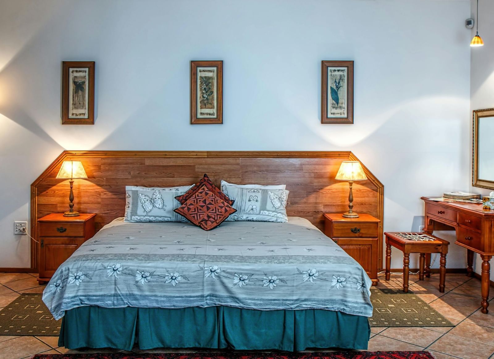 Cosy room with a large neatly made bed, wooden furniture, and framed wall art