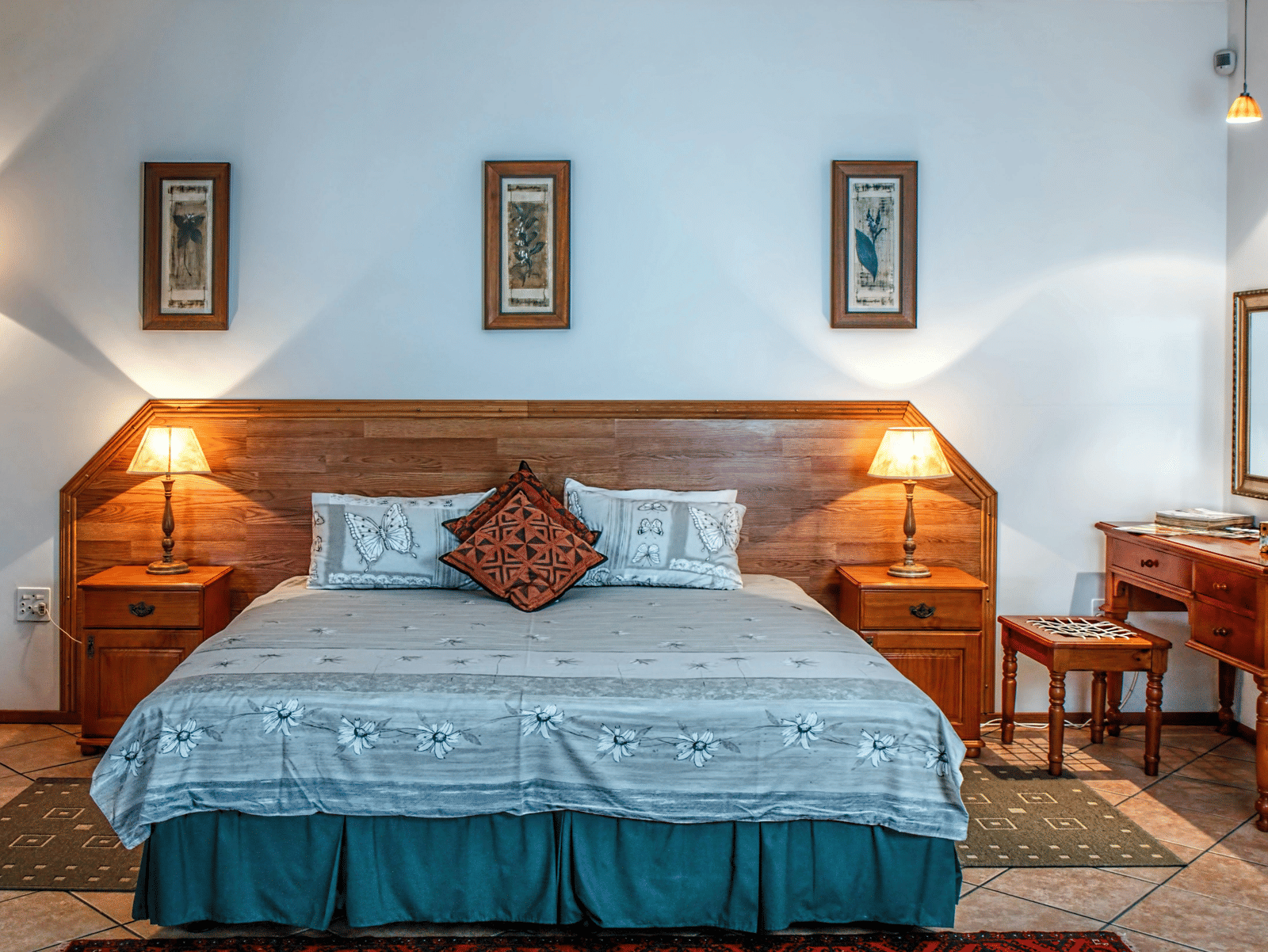 Front view shot of a bedroom featuring a double bed with bright table lamps besides the bed on both sides.