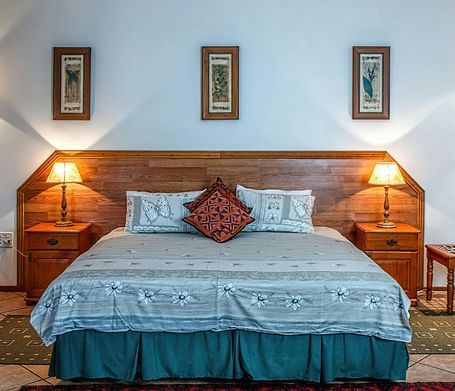 Front view shot of a bedroom featuring a double bed with bright table lamps besides the bed on both sides.