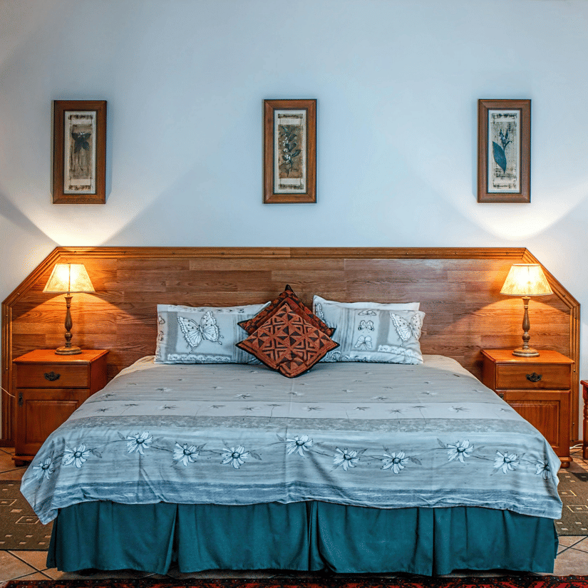 Front view shot of a bedroom featuring a double bed with bright table lamps besides the bed on both sides.