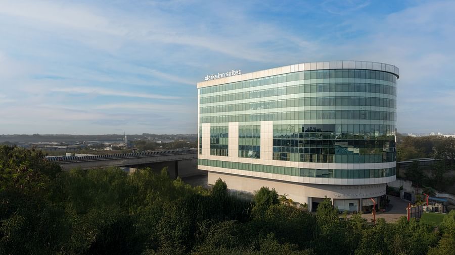 Daylight view of modern multi-storey glass hotel surrounded by landscaped greenery at Clarks Inn Suites, Hyderabad