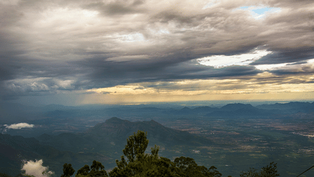 Dramatic cloudscape over a valley with layered hills and distant plains.