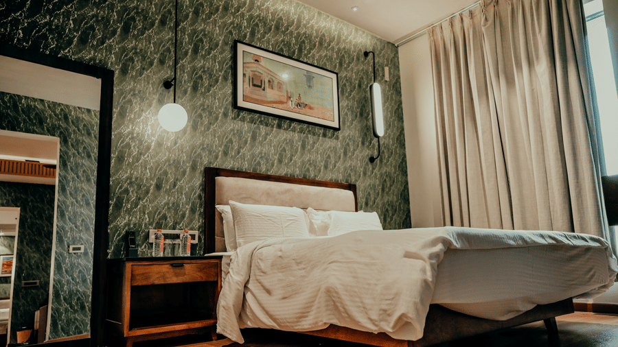 The comfortable, stylishly decorated guest room features soft lighting and a plush white duvet at Pushkara Resort & Spa.