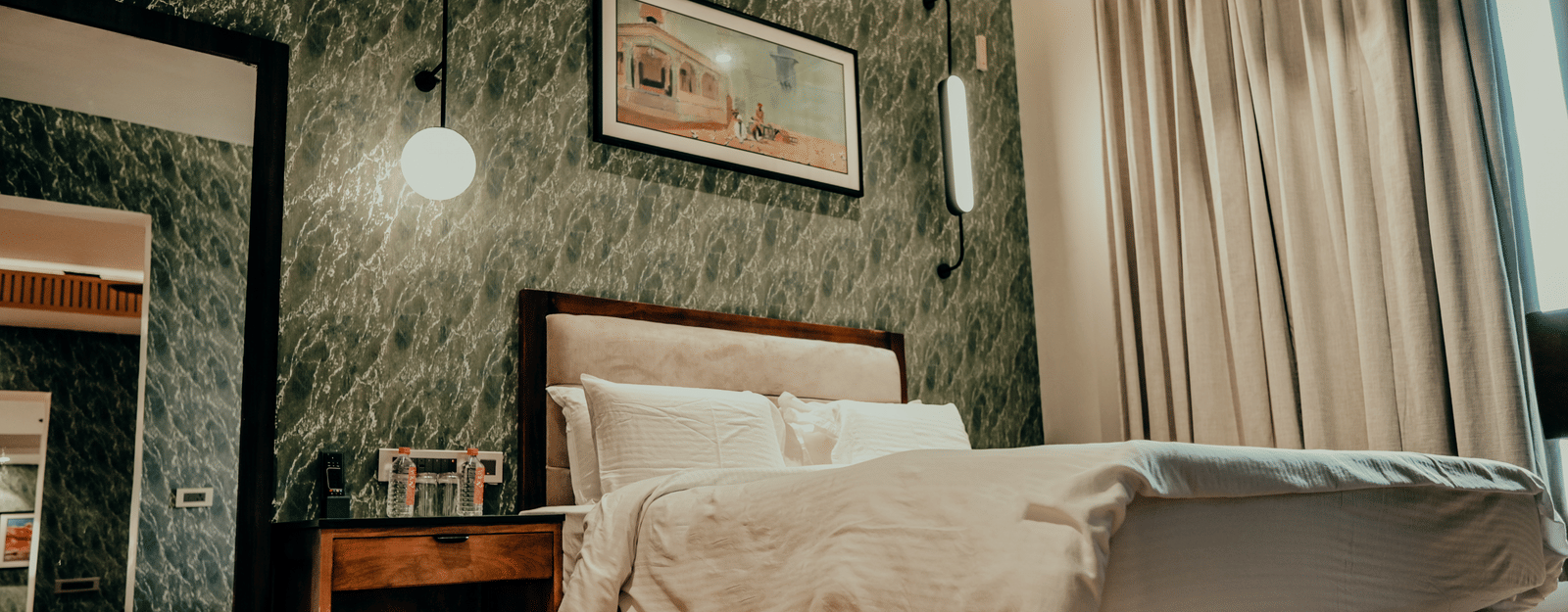 The comfortable, stylishly decorated guest room features soft lighting and a plush white duvet at Pushkara Resort & Spa.