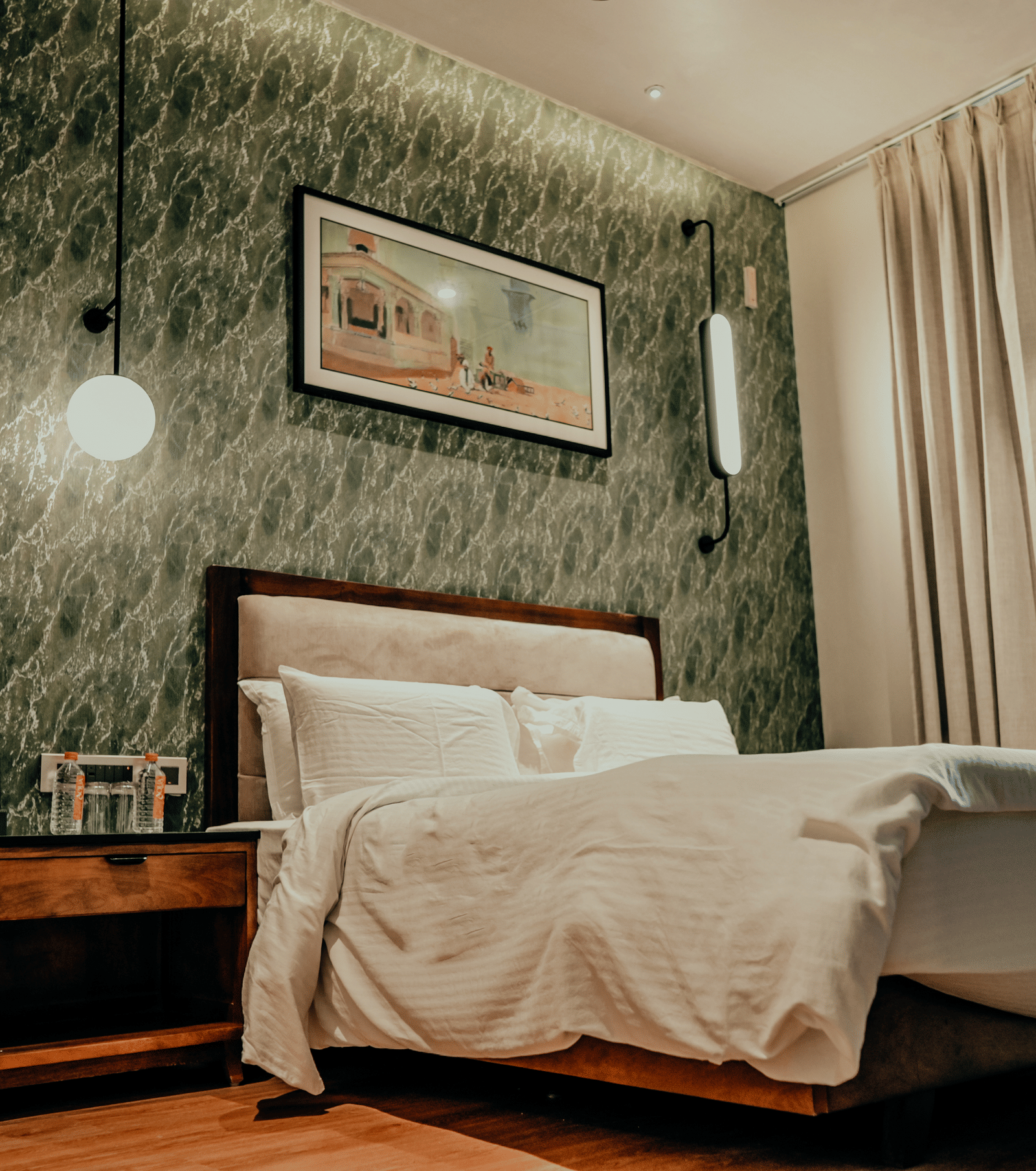 The comfortable, stylishly decorated guest room features soft lighting and a plush white duvet at Pushkara Resort & Spa.