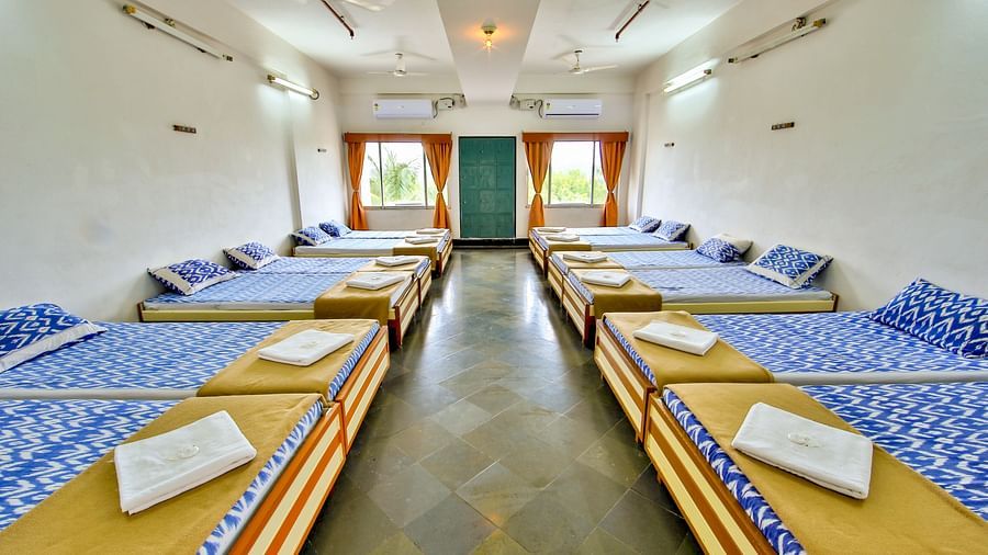 A full view of beds with bedding arranged in two rows in a room | Hotel Sahara