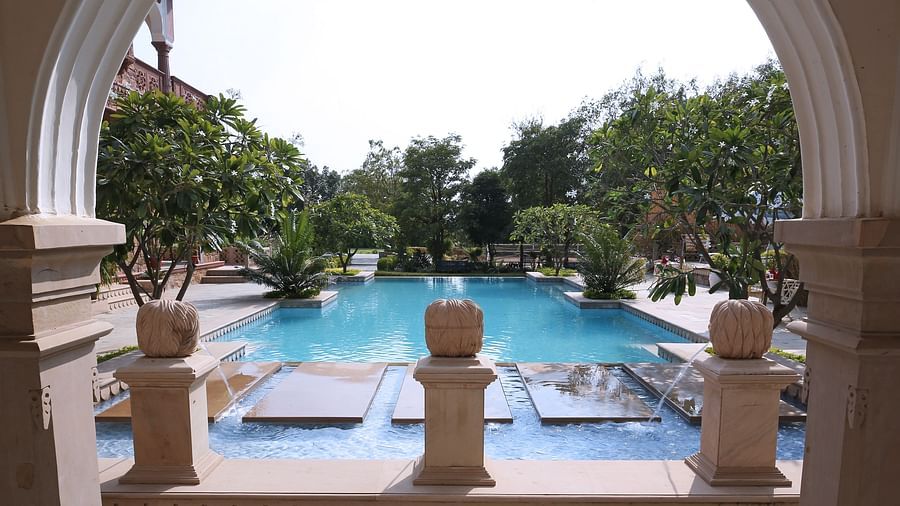 A beautiful swimming pool surrounded by arches and lush greenery - Khas Bagh, Jaipur.
