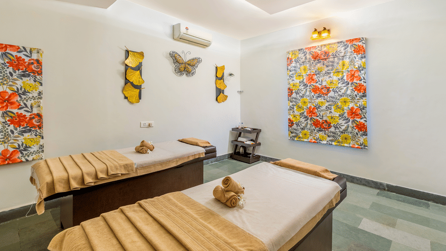 A wide view of a spa room containing two treatment beds and colourful wall art | Anandam Jungle Retreat Resort, Udaipur