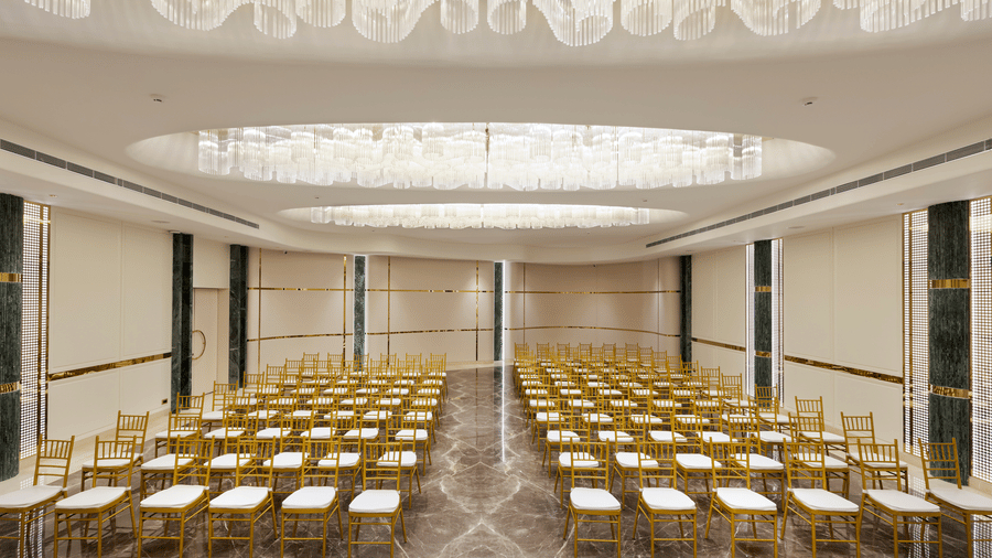 Emerald Hall arranged in theatre-style seating with gold chairs at Jenney Residency, perfect for conferences and large gatherings.
