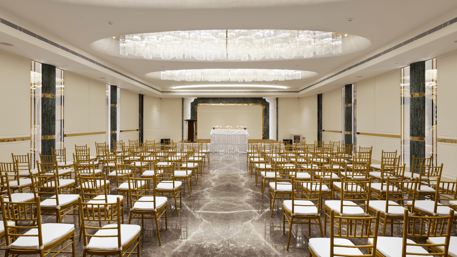 Emerald Hall at Jenneys Residency, featuring crystal chandeliers, polished marble flooring, and gold-accented pillars, is ideal for grand events.