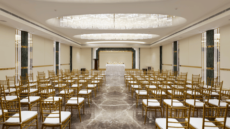 Emerald Hall at Jenneys Residency, featuring crystal chandeliers, polished marble flooring, and gold-accented pillars, is ideal for grand events.