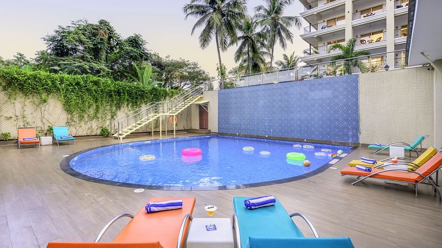 Swimming pool at Golden Tulip, Candolim, Goa, surrounded by modern buildings and leisure seating.