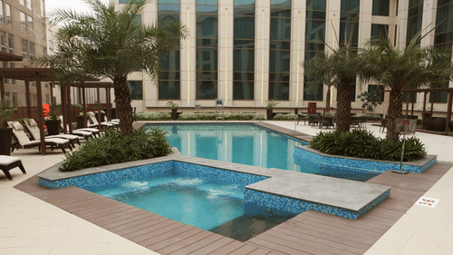 Image of the swimming pool surrounded by trees and buildings at Pride Plaza Hotel in New Delhi