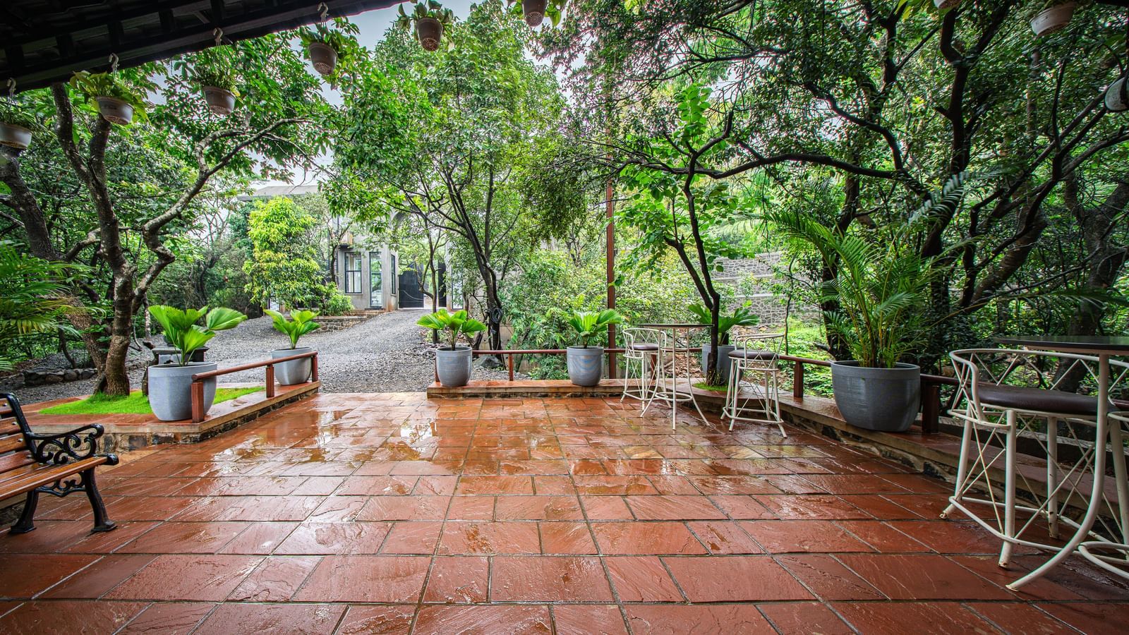 A covered outdoor patio with a tiled floor, wet from the rain, and a view of a lush green forest - Tranquil Piedmont Estates & Resort