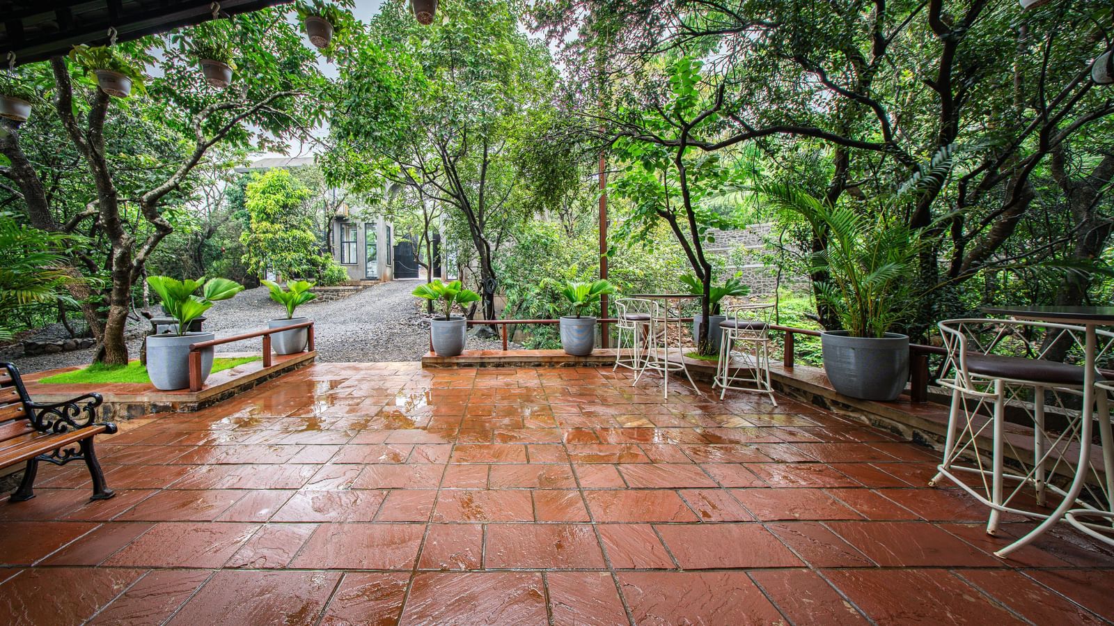 A covered outdoor patio with a tiled floor, wet from the rain, and a view of a lush green forest - Tranquil Piedmont Estates & Resort
