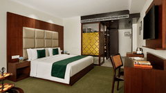 An image of our club room with a double bed placed in front of a wall mounted television - Deventure Sarovar Portico, Patel Nagar