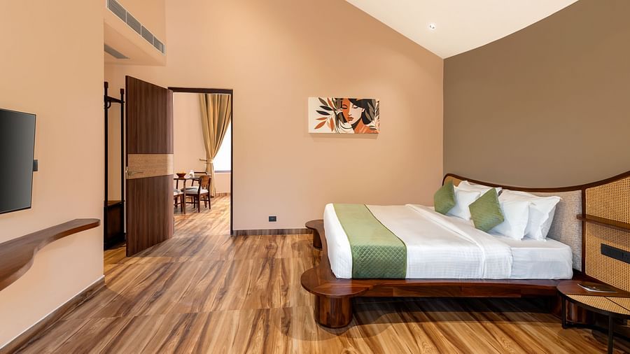 Luxury Villa with Sitout showcases a king size bedroom with a wooden bed frame, white bedding, and a door leading to another room at The Qualia Resort Club & Brewery, Udaipur.