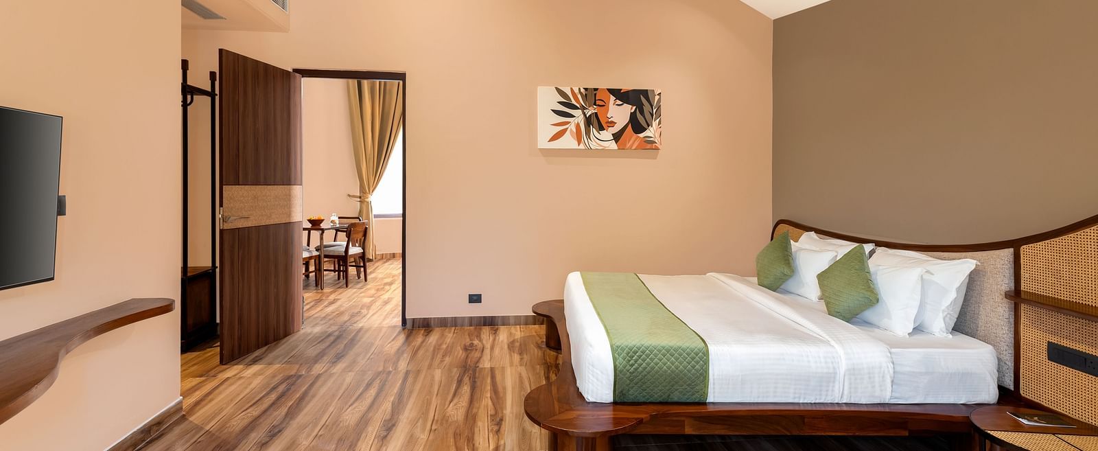 Luxury Villa with Sitout featuring a king size bed with a green-accented throw and headboard, complemented by wooden furniture and a view into an adjacent room at The Qualia Resort Club & Brewery, Udaipur.