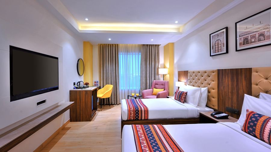 An image of twin beds in our Deluxe Rooms placed in front of a television - Golden Tulip, Agra