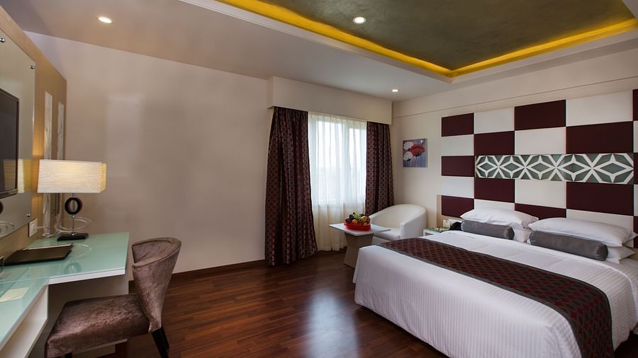A double bed with a study table opposite it inside Superior Room Hotel Pai Viceroy Tirupathi 
