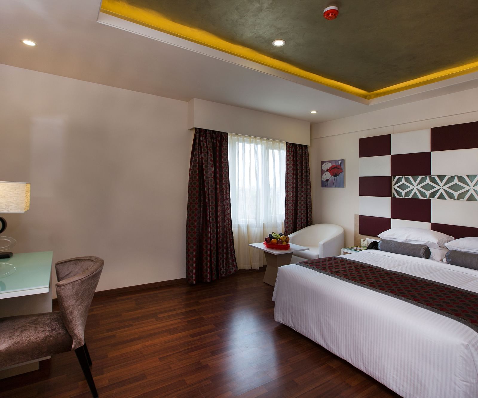 A double bed with a study table opposite it inside Superior Room Hotel Pai Viceroy Tirupathi 