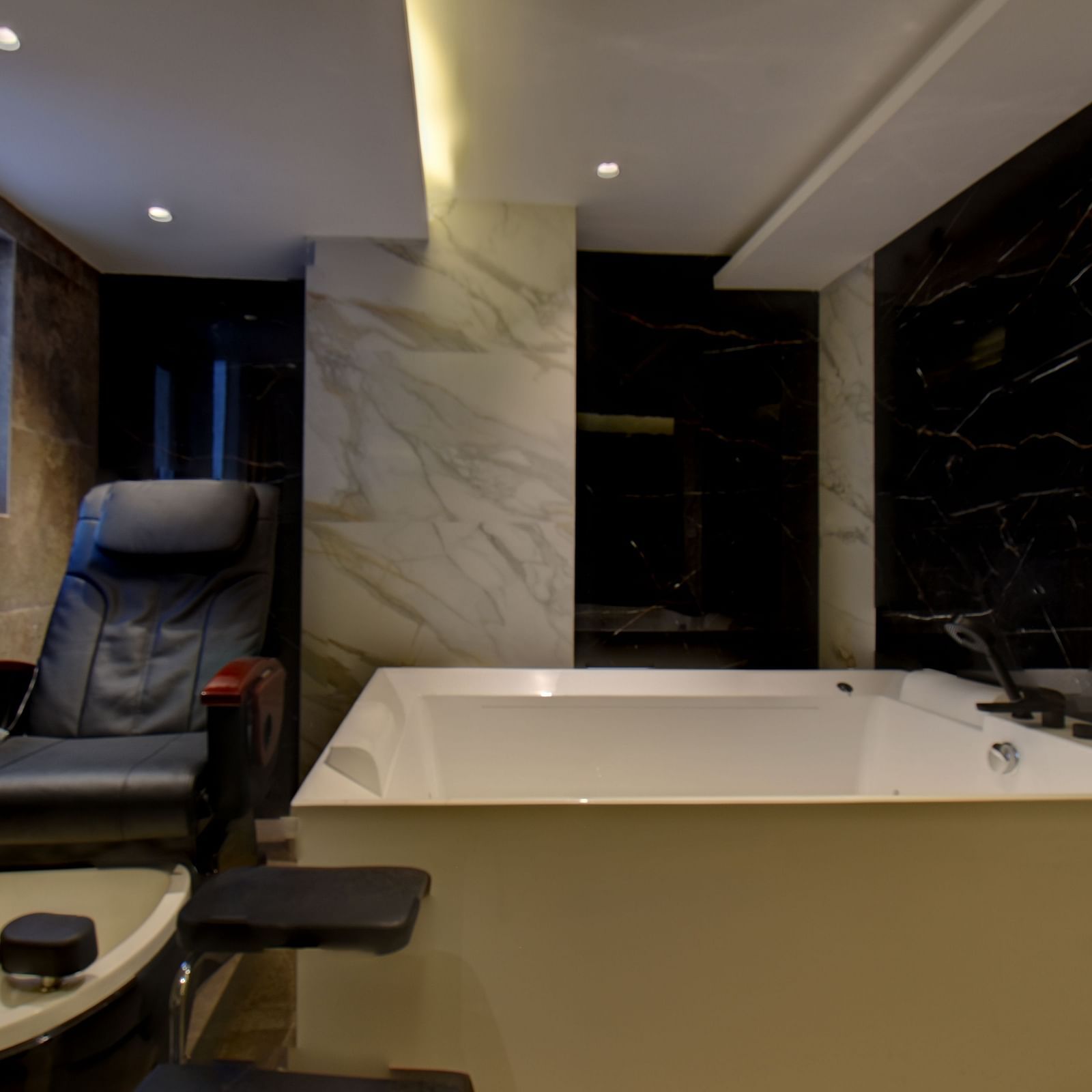 A Jacuzzi and a massage chair at  The SSK Solitaire Boutique Hotel & Spa, Gangapur Road - Nashik with warm lighting. 