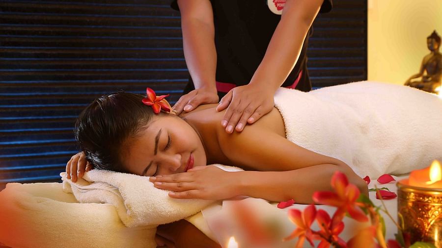 A woman lying on her stomach with her eyes closed and receiving massages on her back at Ocean Spa, UDS Group of Hotels
