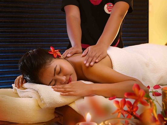 A woman lying on her stomach with her eyes closed and receiving massages on her back at Ocean Spa, UDS Group of Hotels