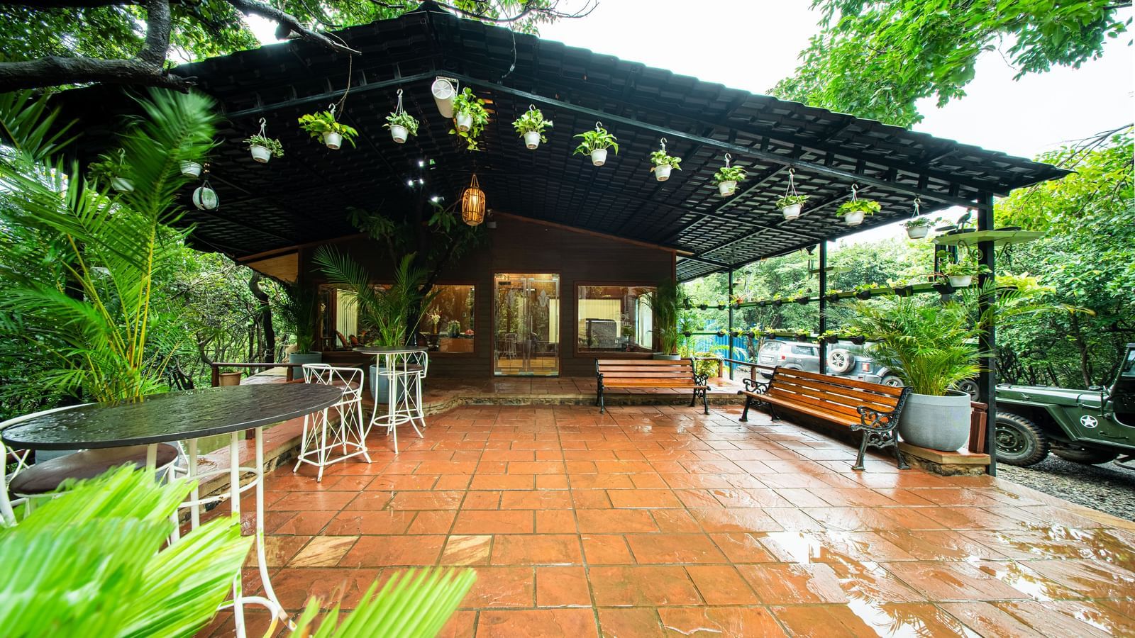 A wooden outdoor dining area with tables and chairs, illuminated by hanging lights and surrounded by dense green trees - Tranquil Piedmont Estates & Resort