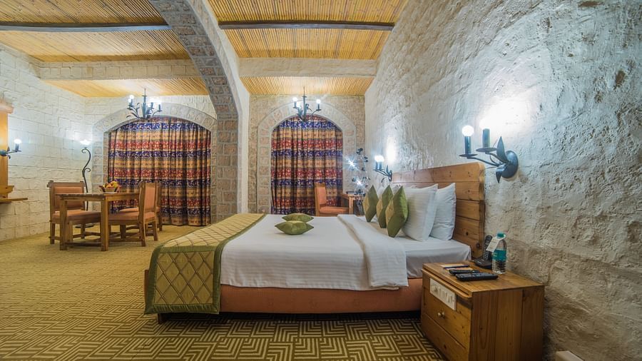 A charming hotel room with a comfortable bed, beamed ceiling, and checkered curtains, exuding a warm ambiance at  Sitara Luxury Hotel in Hyderabad near Ramoji Film City.