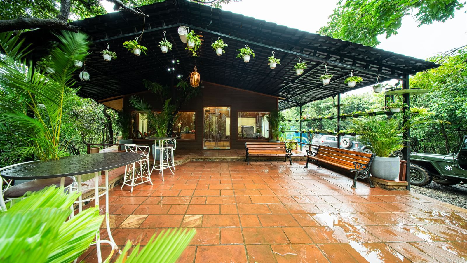 A wooden outdoor dining area with tables and chairs, illuminated by hanging lights and surrounded by dense green trees - Tranquil Piedmont Estates & Resort