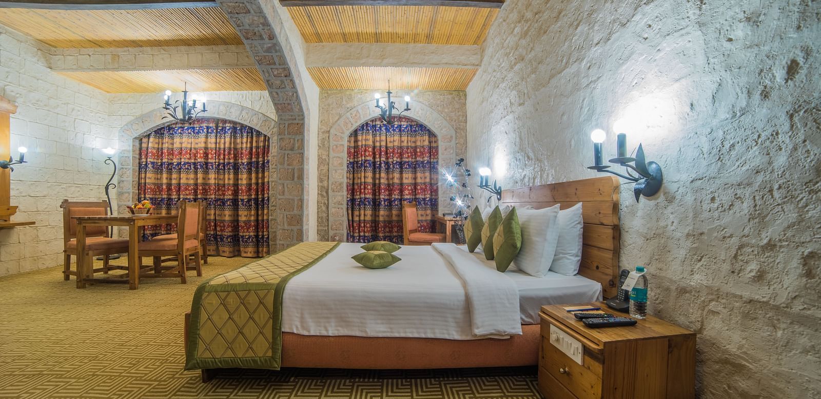 A charming hotel room with a comfortable bed, beamed ceiling, and checkered curtains, exuding a warm ambiance at  Sitara Luxury Hotel in Hyderabad near Ramoji Film City.