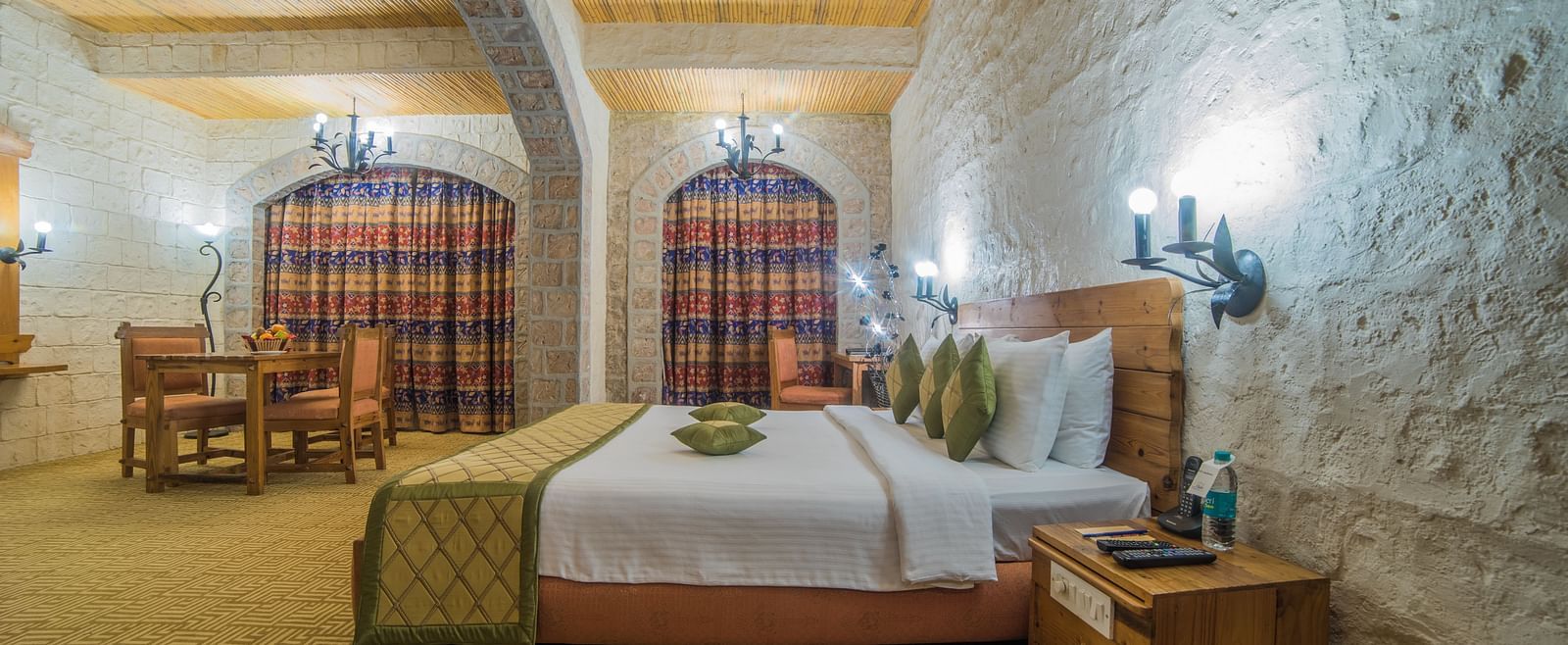 A charming hotel room with a comfortable bed, beamed ceiling, and checkered curtains, exuding a warm ambiance at  Sitara Luxury Hotel in Hyderabad near Ramoji Film City.