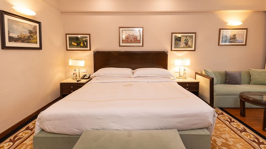 image of the king size bed with white sheets on it and table lamps on either sides of it at our heritage balcony room - The Claridges New Delhi