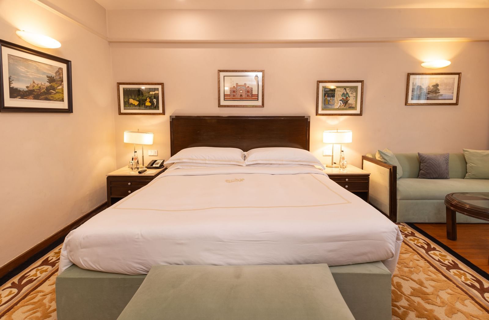 image of the king size bed with white sheets on it and table lamps on either sides of it at our heritage balcony room - The Claridges New Delhi