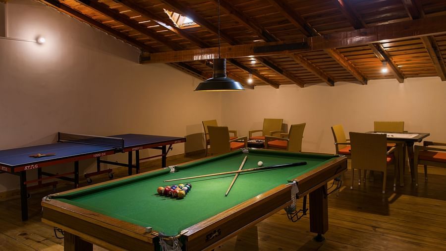  A well-maintained pool table in a cozy room with a unique sloped ceiling, providing a recreational space for guests to relax and enjoy - Digantaa Resort in Mukteshwar