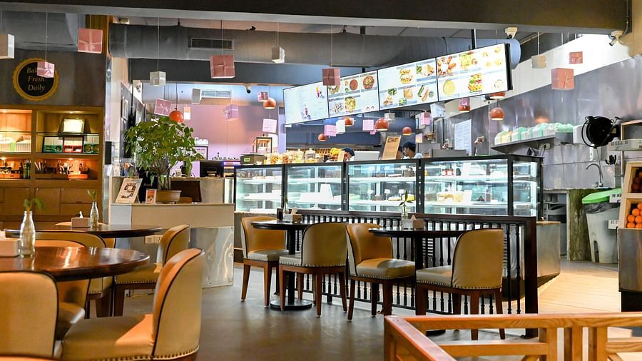 A cosy restaurant with tables and chairs in front of an open kitchen where food is displayed